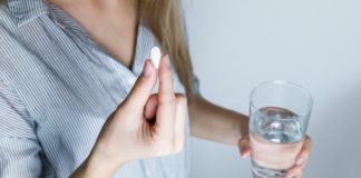 A woman with glass of water and a pill