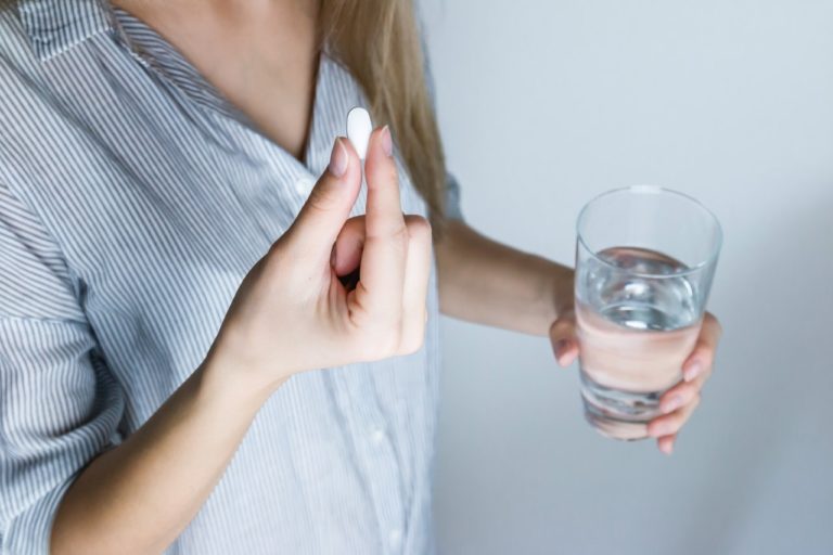 A woman with glass of water and a pill