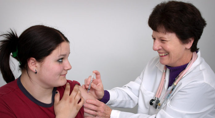 Girl receiving cervical cancer shot from doctor