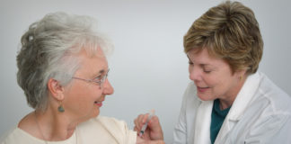 A nurse giving vaccine to an old lady
