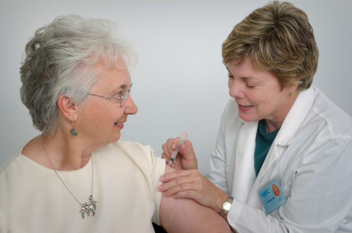 A nurse giving vaccine to an old lady